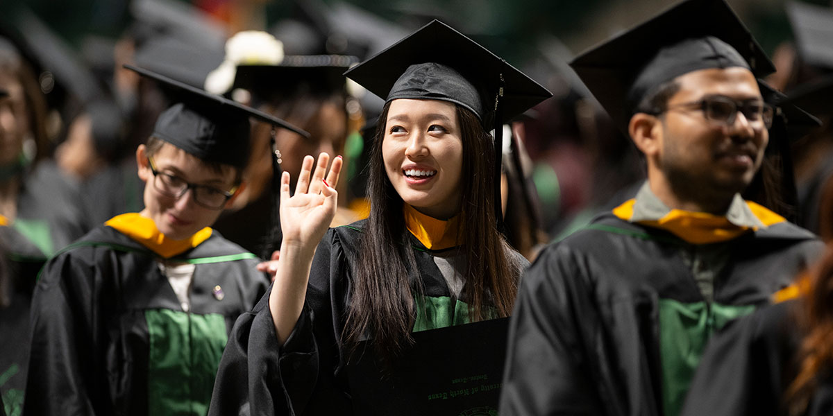 A graduate waving during commencement